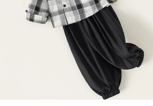 Flat lay detail of boys' black and white plaid shirt and casual jogger pants outfit