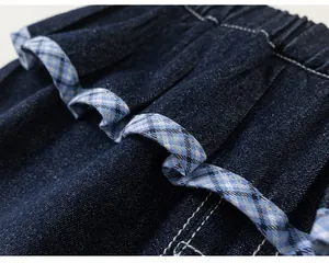Detail of elastic waist with ruffles and blue-white checkered ribbon on denim clothes