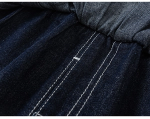 Detailed close-up of dark blue denim trousers with elastic waistband and white contrast stitching