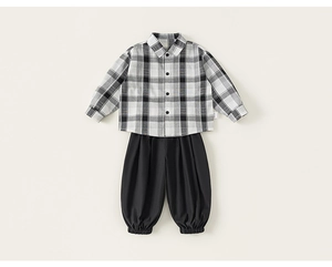 Detail view of boys plaid shirt and black jogger pants laid flat on a beige background