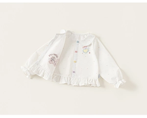 Close-up of girls' polka dot blouse featuring colorful buttons and frill hem details