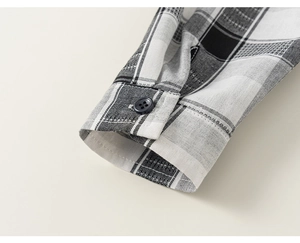 Close-up of classic black and white plaid shirt cuff with fine stitching and resin button