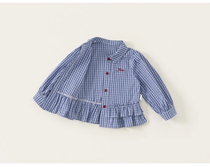 Close-up of blue gingham girls shirt with red buttons and ruffled hem detailing