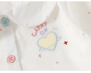 Detailed close-up of white cotton shirt with colorful dots and Carry On embroidery