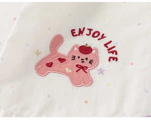 Detailed view of pink cartoon cat embroidery with Enjoy Life text on white knit vest