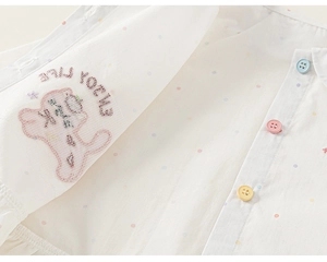 Detail of white cotton shirt with colorful polka dots, vibrant buttons and dog embroidery