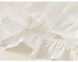 Close-up of white girls' shirt detail featuring colorful polka dots and ruffle edges