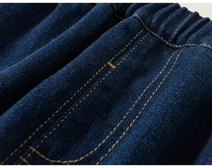 Close-up of indigo denim trousers showing elastic waistband and yellow contrast stitching