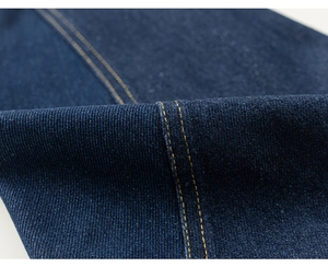 Macro shot of dark blue denim fabric with decorative orange contrast stitching