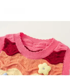 Detail of colorful knitted vest with wave pattern and 3D floral accent for girls
