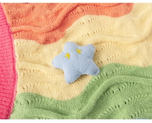 Detailed close-up of colorful wavy knit pattern with a blue plush star patch decoration