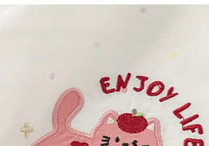 Detail der süßen Katzenstickerei und Enjoy Life Text auf gepunktetem Baumwollstoff
