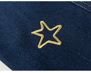 Close-up of dark blue denim fabric with gold star embroidery and fine stitching detail