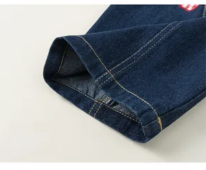 Detail der dunkelblauen Jeanshose mit gelben Kontrastnähten und weiten Beinabschlüssen
