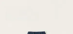 Dettaglio dei pantaloni in denim blu scuro per bambini con vita elastica e decorazioni a fiocco