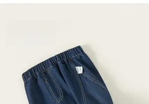 Dettaglio ravvicinato dell'elastico in vita e dell'etichetta su jeans blu scuro per bambina