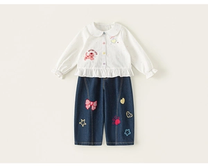 Detail der weißen Mädchen-Baumwollbluse mit Cartoon-Katzenstickerei und Rüschensaum