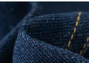Vista macro del tessuto denim blu scuro con cuciture gialle sui pantaloni per bambini