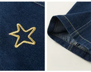 Dettaglio ricamo stella gialla e orlo a gamba larga su pantaloni di jeans blu per bimba