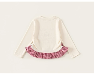 Detail view of cream toddler top with red checkered ruffle hem and soft knitted fabric