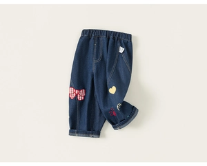 Dettaglio di jeans da bambina con fiocco a scacchi rossi e stampe a fumetti colorate