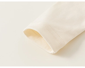 Close-up of ribbed cuffs and fine stitching on children's cream-colored cotton shirt