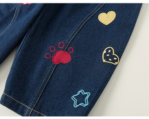 Dettaglio di ricami a cuore e zampa su pantaloni in denim blu scuro per bambini