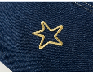 Dettaglio ricamo stella dorata su tessuto denim blu scuro per pantaloni da bambina
