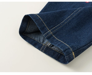 Dettaglio dei jeans da bambina con cuciture gialle a contrasto e tessuto denim blu scuro