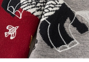 Detail of red and grey knitted fabric with fine bird embroidery and wavy patterns