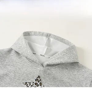 Detail des grauen Hoodie-Ausschnitts mit Leoparden-Stern-Patch und weichem Strick