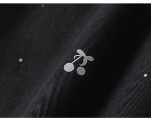 Macro λεπτομέρεια μαύρου υφάσματος twill με μεταλλικό ασημί σχέδιο με κεράσια