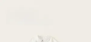 Dettaglio maglia bianca per bambini con colletto Peter Pan, pois colorati e bottone blu
