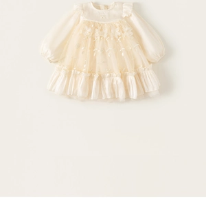 Close-up of ruffled collar and floral lace embroidery on creamy white girl's mesh dress