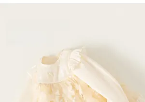 Detailed view of light cream girls tulle dress with 3D floral appliques and bow detail