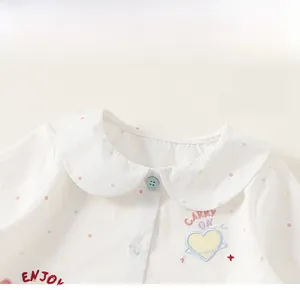 Dettaglio di una camicia bianca da bambina con colletto Peter Pan e ricami colorati