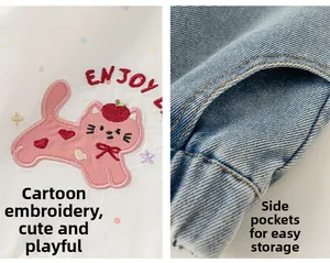 Dettaglio top bianco con ricamo a gatto e tasca laterale dei pantaloni in denim blu