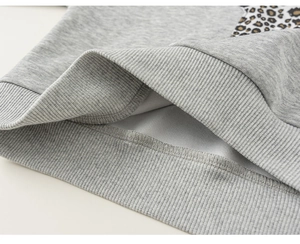Detailansicht des Rippbündchens und Leopardenmusters am grauen Kinder-Kapuzenpullover