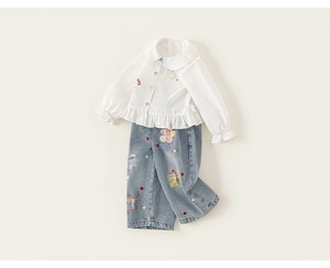 Dettaglio camicia in cotone bianco da bambina con bottoni colorati e ricamo a cuore