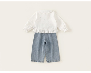 Vista dettagliata posteriore di una camicia bianca con volant e jeans blu chiaro per bambina
