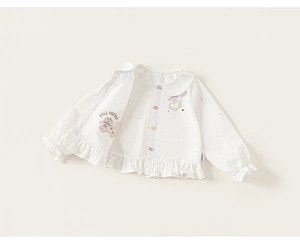 Dettaglio di camicia in cotone bianco per bambina con pois e bottoni colorati