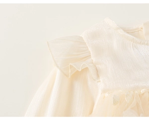 Detail of cream girls mesh dress showing pearl satin texture and layered ruffle sleeves