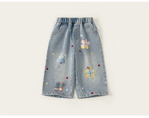 Dettaglio dei pantaloni in denim azzurro per bambina con ricami a fiori arcobaleno colorati