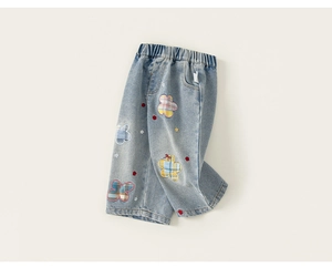 Dettaglio del ricamo floreale colorato e delle toppe sul pantalone in denim chiaro