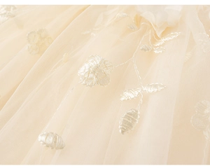 Close-up of delicate floral embroidery on lightweight beige mesh tulle girl's dress