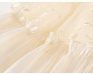 Detailed view of the layered off-white tulle fabric with delicate leaf embroidery and pleats