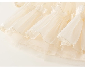 Detail of layered cream tulle and pleated chiffon ruffles on girls' mesh dress