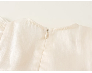 Close-up of invisible zipper and striped texture on a cream mesh girl's dress