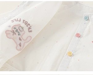 Dettaglio camicia in cotone bianco per bambina con pois colorati e bottoni vivaci