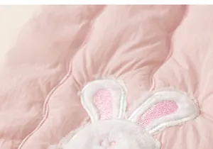 Close-up of pink quilted fabric featuring a soft rabbit cartoon embroidery for kids